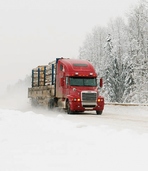 Red semi truck drives down snowy road